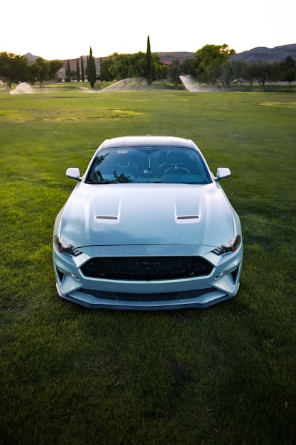A sleek sports car parked on a vibrant green golf course during sunset.