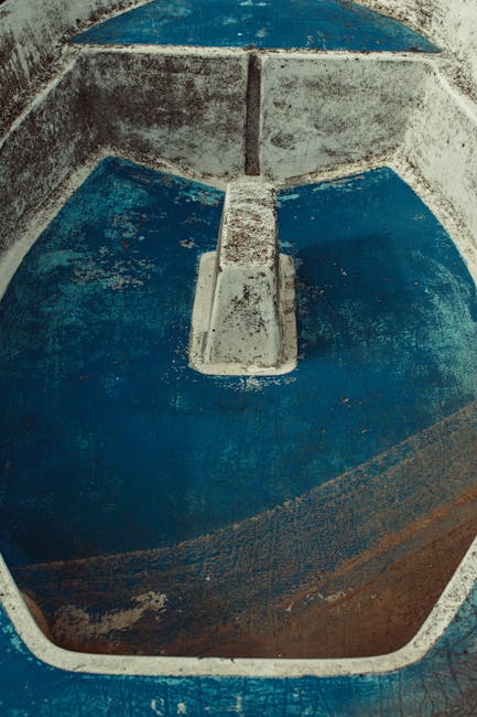 A rustic, empty concrete basin featuring a worn blue surface with a retro vibe, captured vertically.